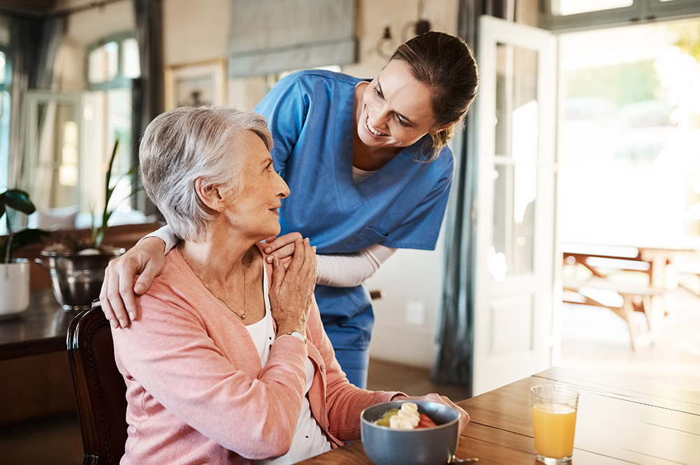 Carer and senior woman in dining hall in care home